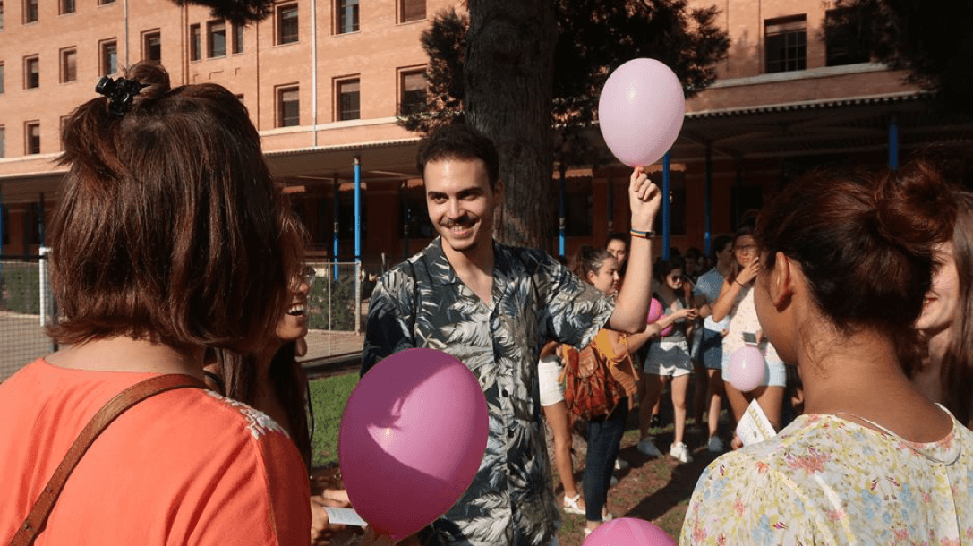 Students at an event holding pink balloons.
